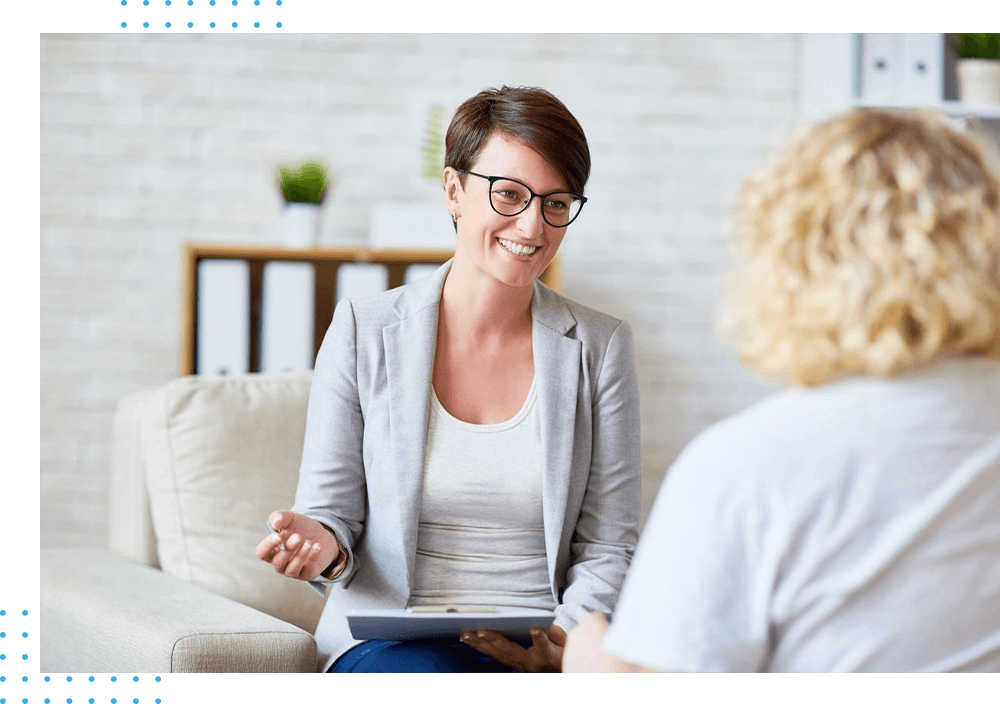 A woman sitting on the couch talking to another person.