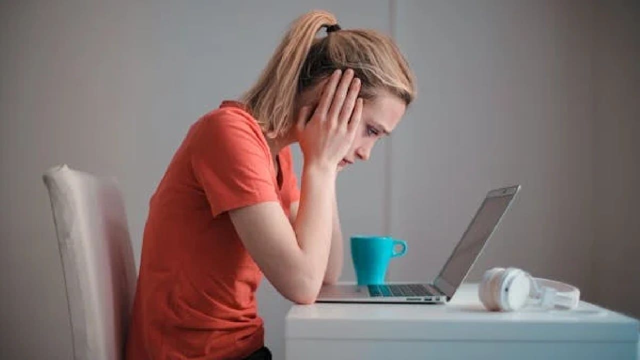 A woman sitting at a table with her hand on the ear of another person.