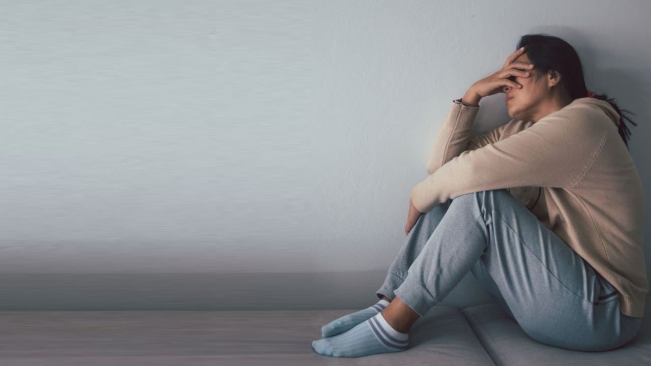 A person sitting on the ground with their hands in her head.