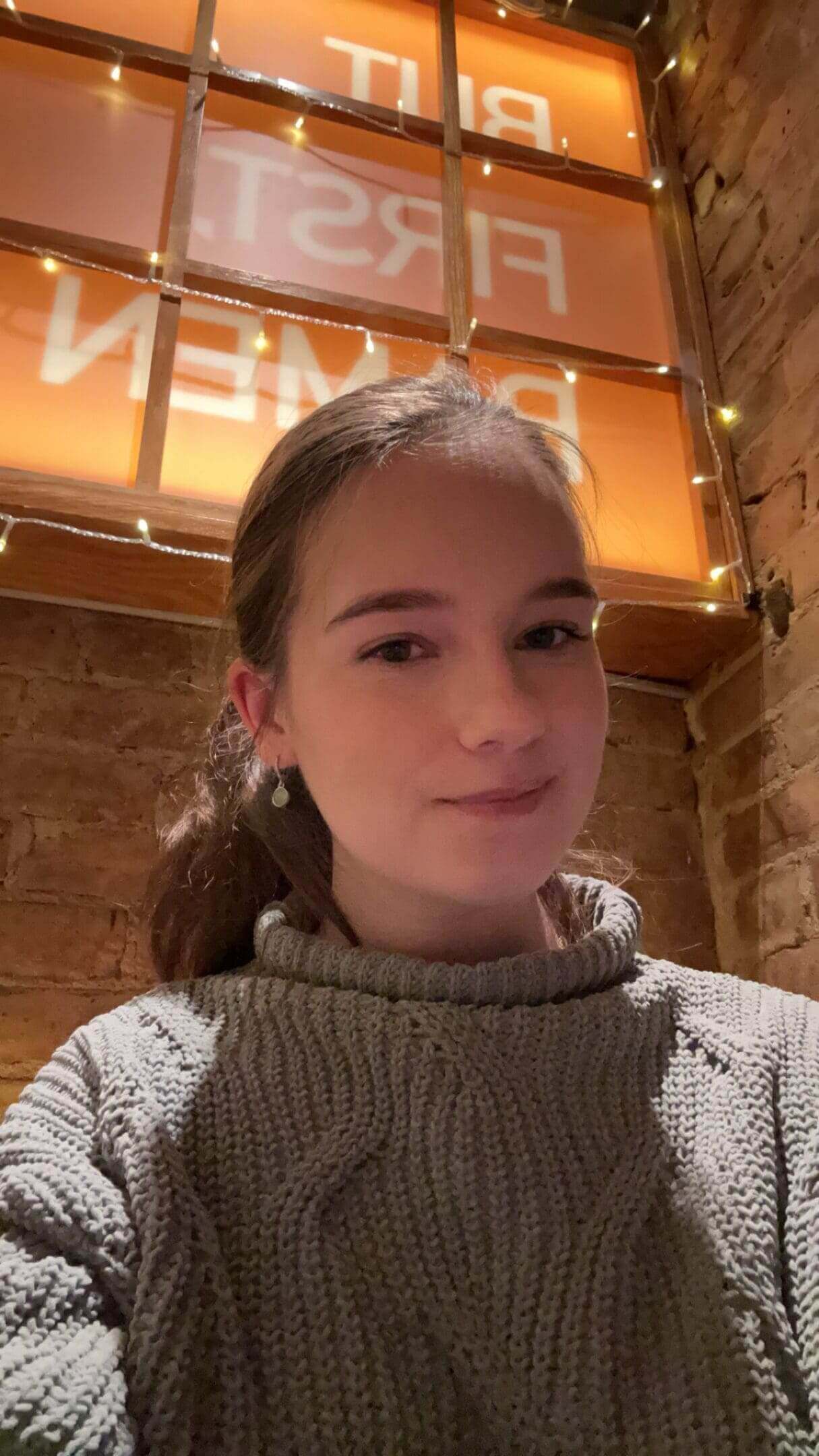 Person smiling in cozy, warmly lit room.